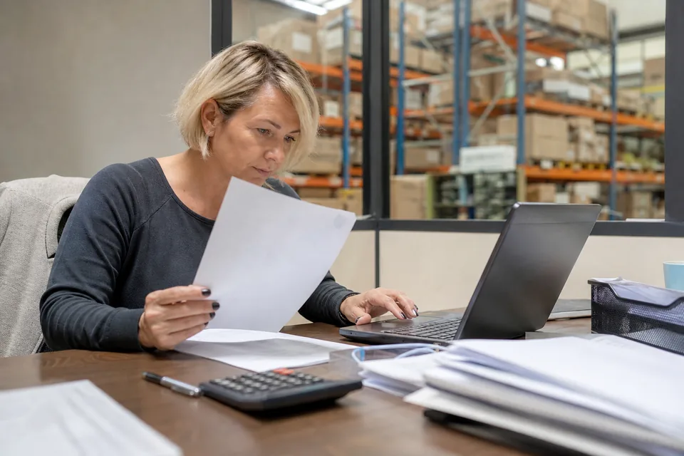 Dyrektorka finansowa firmy dystrybucyjnej porównuje ofertę limitu faktoringowego z banku z ofertami na laptopie